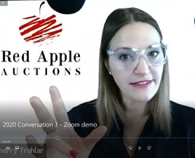 Screenshot of virtual gala auctioneer Sherry Truhlar in front of Red Apple Auctions' logo 